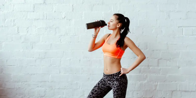 Junge Frau in Sportbekleidung trinkt einen Protein-Shake