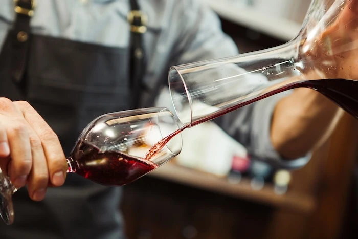Schmuckbild: Sommelier, der ein Glas Rotwein mit einem Dekanter einschenkt.