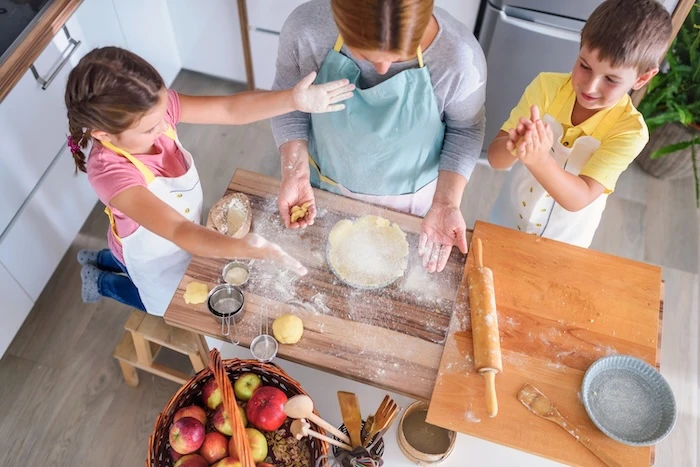 Kinder kneten zusammen mit ihrer Mutter Teig in der Küche