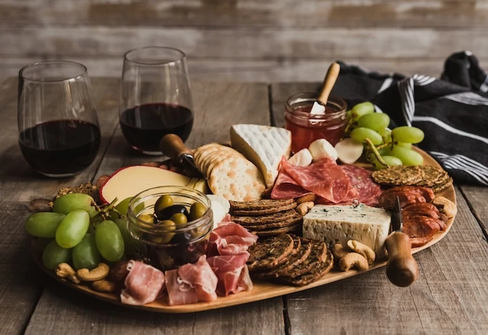 Schmuckbild: Charcuterie Board mit Wurst und Käse, dahinter zwei Gläser mit Rotwein.