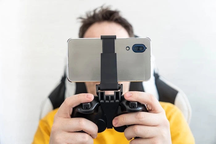 Gamer beim Zocken mit Smartphone in mobilem Gaming-Controller