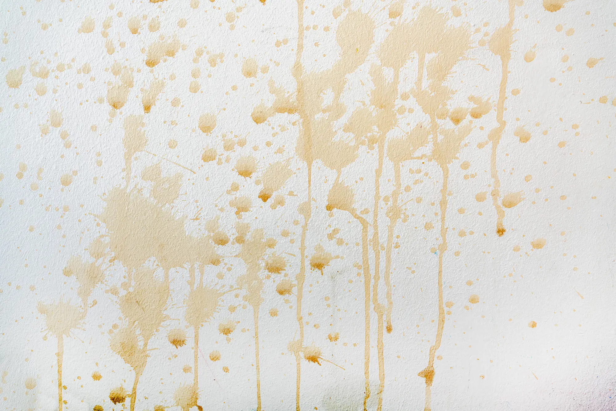 Schmuckbild: Weiße Wand mit vielen hellbraunen Kaffeeflecken