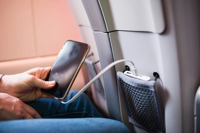 Schmuckbild: Tasche im Flugzeugsitz zum Verstauen deines Handys und tragbaren Ladegeräts – Aufladen unterwegs während des Reisens.