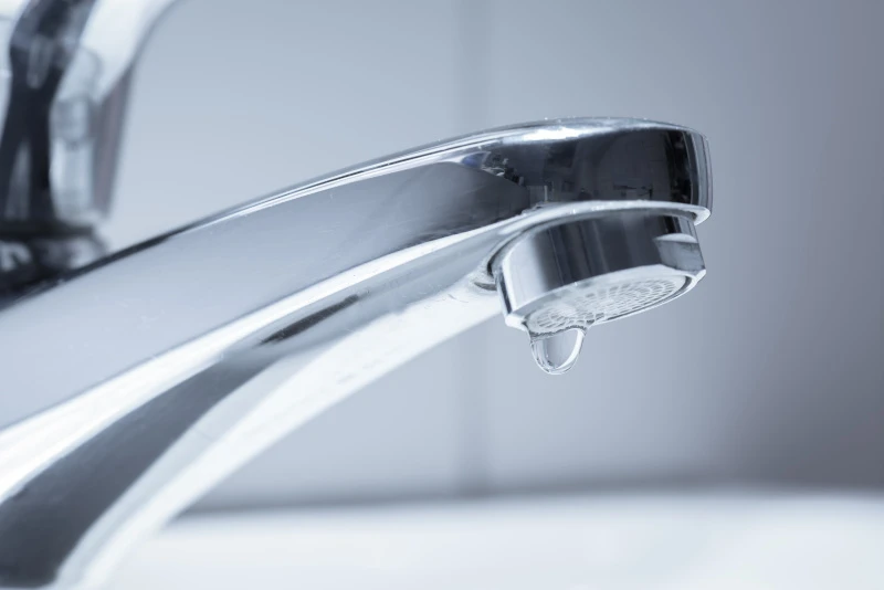 Schmuckbild: Ein silberner Wasserhahn, an dem ein Tropfen Wasser hängt.