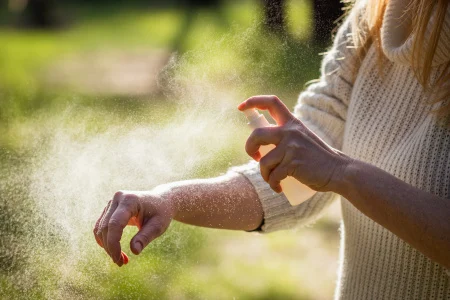 Arme mit Mueckenspray einspruehen