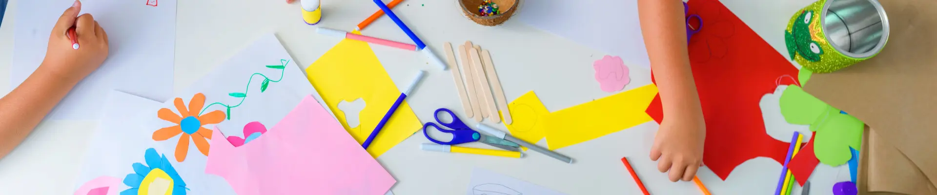 Schmuckbild: Ein Tisch voller Bastel- und Malutensilien, die von Kindern genutzt werden