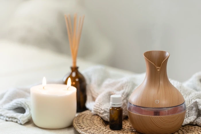 Ein elektrischer Aromaöl-Diffusor, daneben eine Kerze und Duftstäbe.