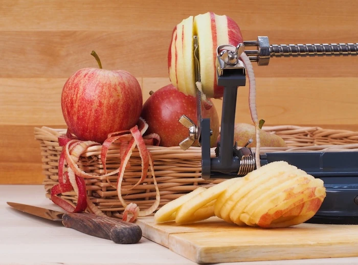 Ein Apfel steckt auf einem Apfelschäler und wird geschält, geschnitten und entkernt