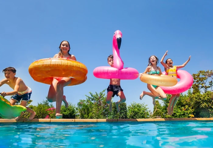 Schmuckbild: Kinder mit verschiedenen aufblasbare Schwimmreifen springen in Pool