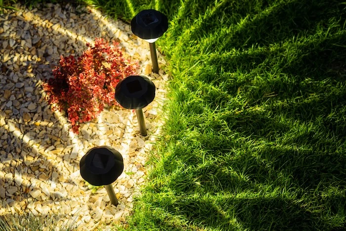 In der Erde steckende Solarleuchten, die einen Garten beleuchten.