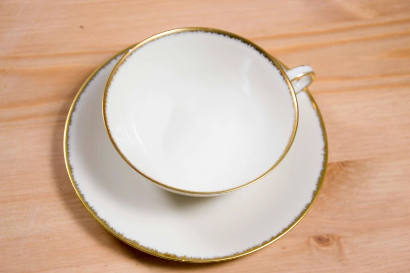 Schmuckbild: Foto eines Tellers mit Goldrand, auf dem eine Tasse mit Goldrand steht