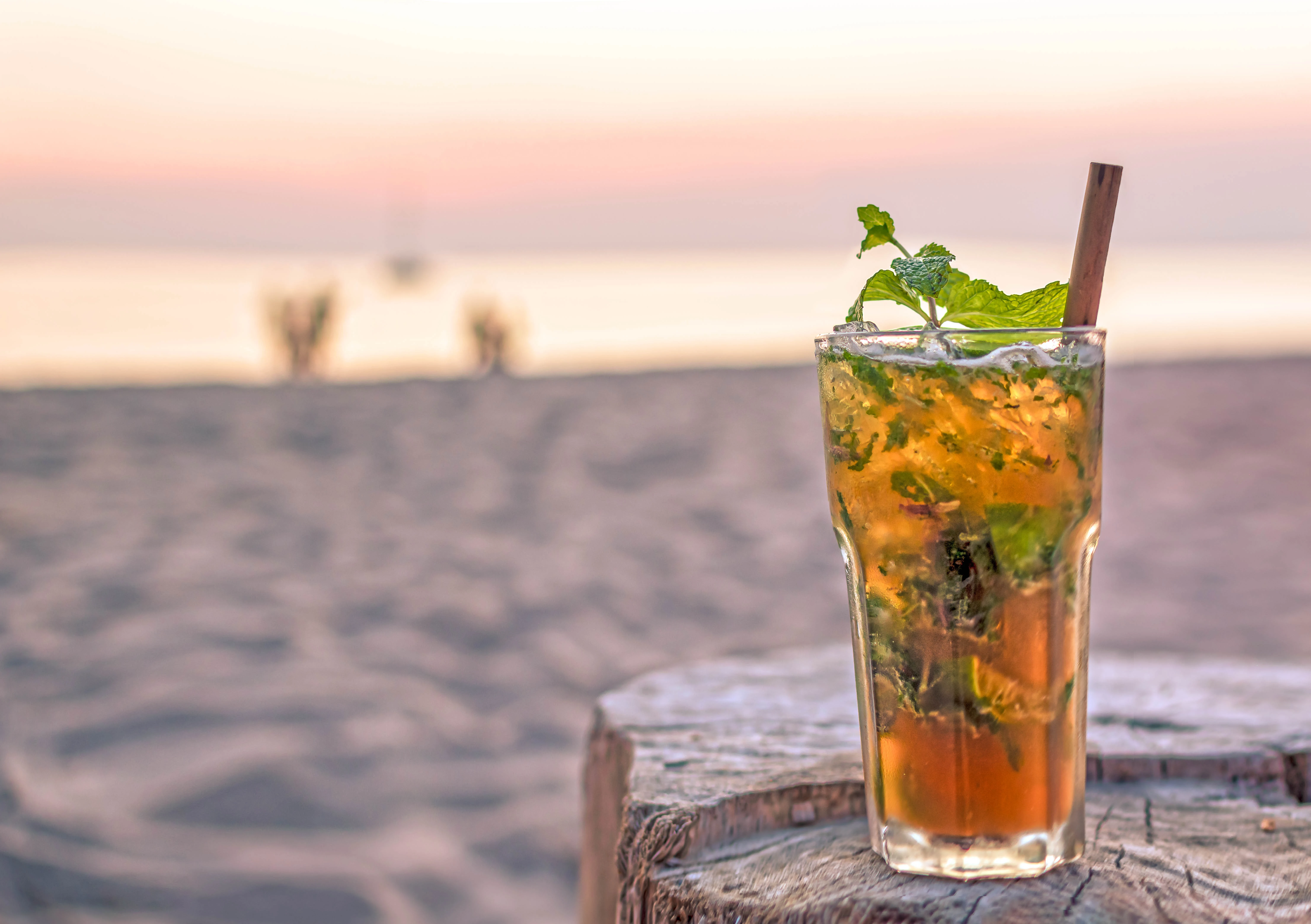 Sommergetränk im Glas auf Holztisch vor Strandkulisse