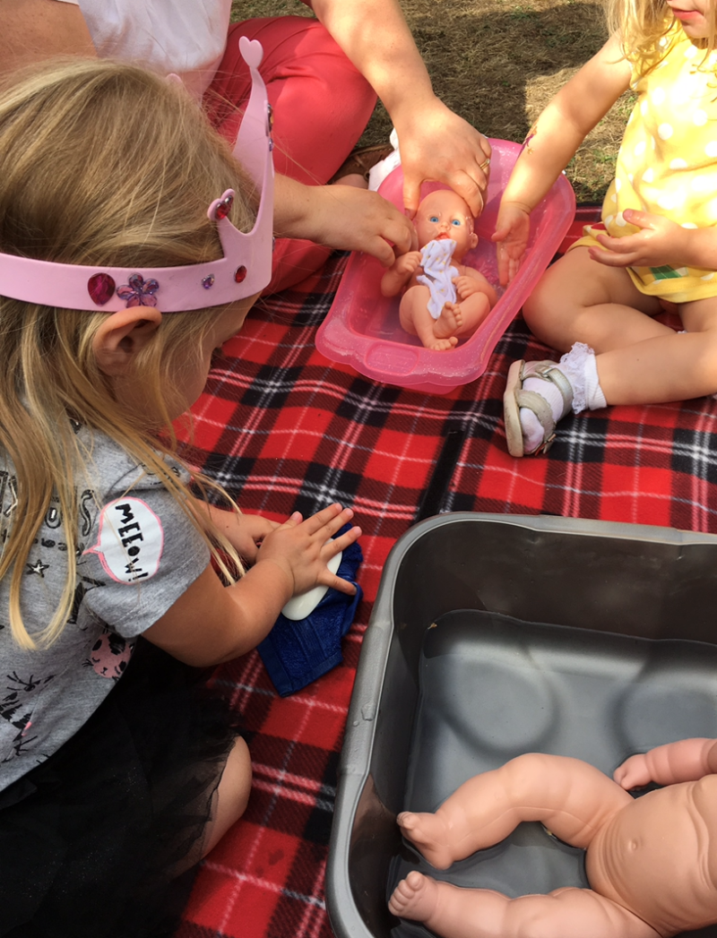 Two children bathing their dolls in a guided play activity
