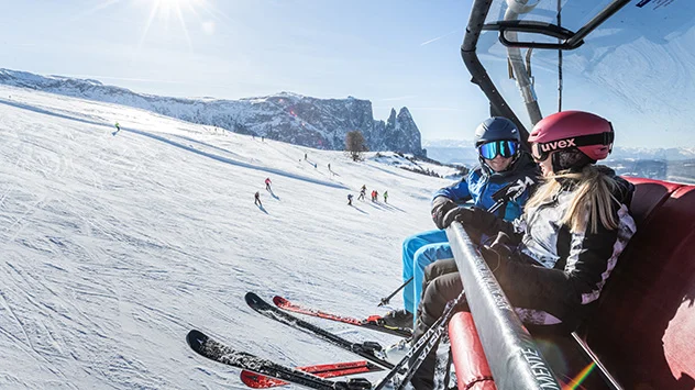 Sonnenskilauf in der Dolomitenregion Seiser Alm - Bild: IDM Südtirol / Harald Wisthaler Skifahrer sitzen in einem Sessellift