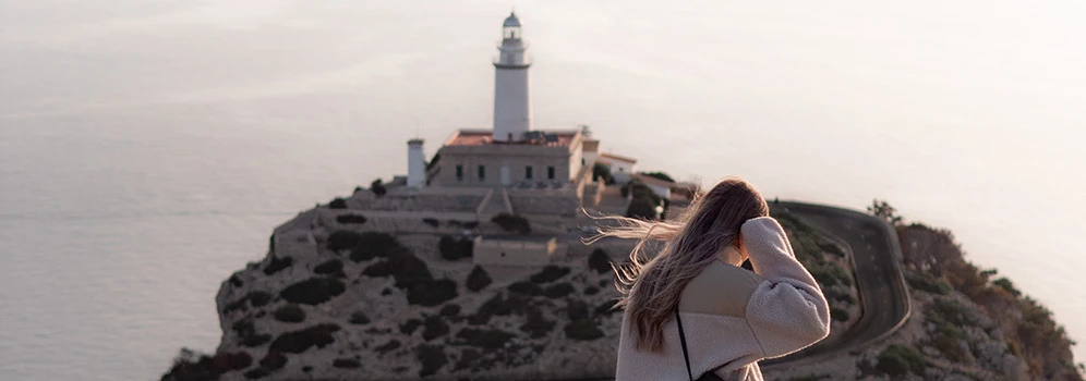 Frau blickt auf den Leuchtturm am Cap de Formentor auf Mallorca
