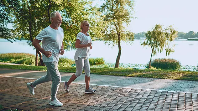 Älterer Mann und ältere Frau joggen zusammen bei gutem Wetter