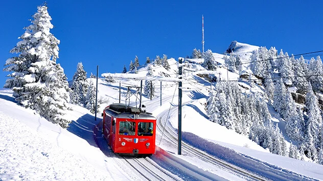 Rote Bahn fährt durch verschneite Berglandschaft