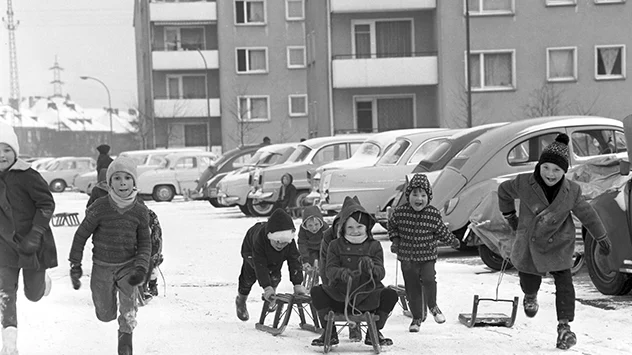 Kinder fahren Schlitten in der Stadt