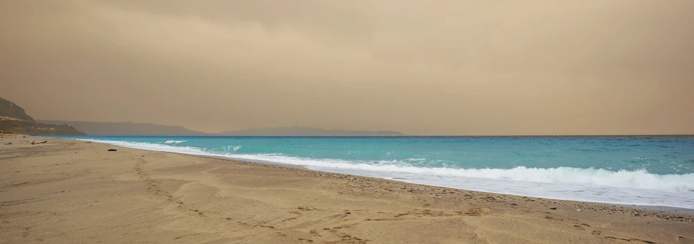 Blick auf das Meer mit einem sandfarbenen Himmel