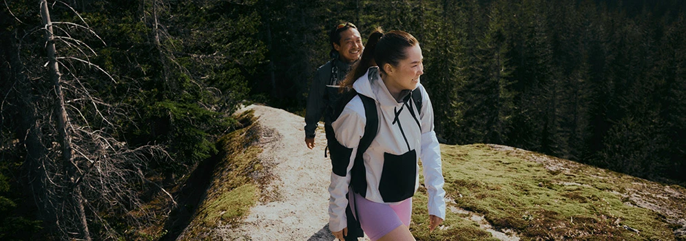Zwei Wanderinnen in GORE-TEX Bekleidung unterwegs in herbstlicher Berglandschaft.