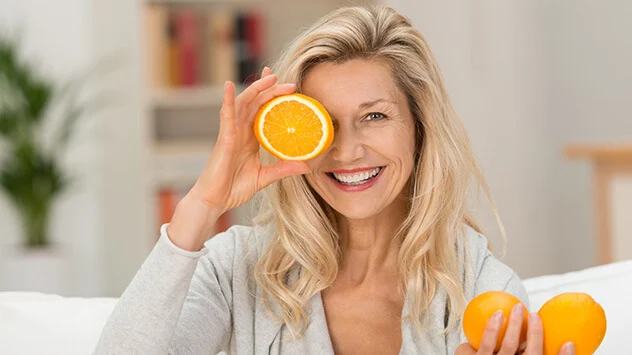Lachende Frau mit Orangen in den Händen