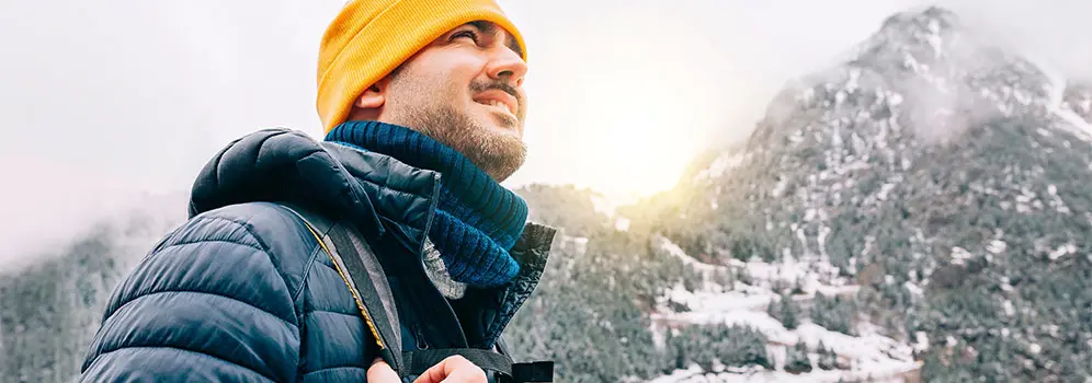 Ein Mann genießt beim Wandern die winterliche Landschaft.