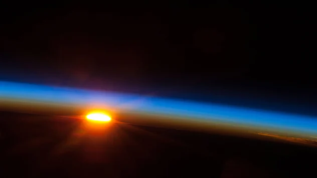 Eine Aufnahme aus der internationalen Raumstation: Die Sonne geht über dem Südpazifik auf. Die Morgenröte ist an dem rötlichen Band zu erkennen. 