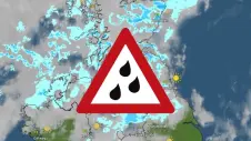 Weather map showing rain in the UK with a warning sign for rainfall