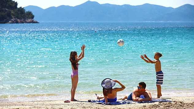 Familie spielt Ball im seichten Wasser