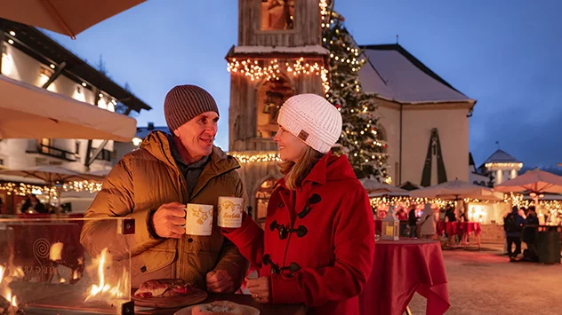 Ein Paar genießt heißen Punsch auf dem Seefelder Weihnachtsmarkt