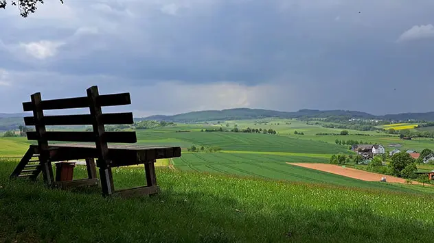 Blick auf Felder und Wiesen in Nordhessen mit dunklen Wolken am Himmel