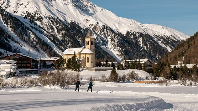 Winterurlaub im Südtiroler Ortlergebiet - Bild: Ferienregion Ortlergebiet/Malthe Wöhler Langläufer auf einer Loipe im Ortlergebiet, im Hintergrund eine Kirche
