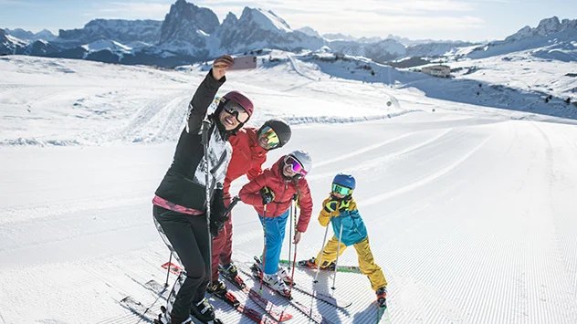 Sonnenskilauf in der Dolomitenregion Seiser Alm - Bild: Dolomiti Superski / Harald Wisthaler Eine Familie macht ein Selfie auf der Skipiste.
