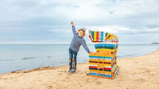 Kind steht vor buntem Strandkorb im Miniaturformat