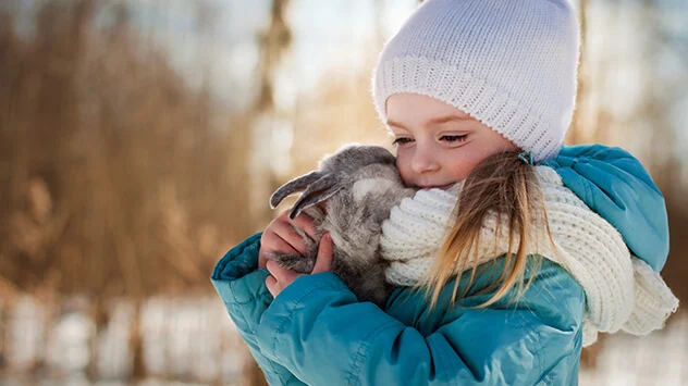 Mädchen kuschelt mit Kaninchen im Winter