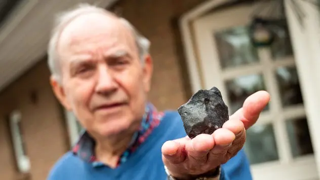Hausbesitzer Wilfried Labusch aus Elmshorn hält den kleinen Meteoriten in der Hand, der in sein Dach eingeschlagen ist.