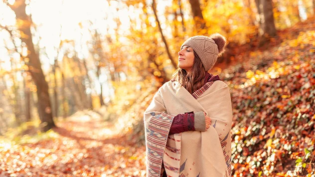 Stricken, Häkeln und Nähen im Herbst Junge Frau steht im Mütze und Schal im Herbst im Wald