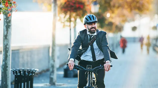 Ein Mann im Anzug fährt mit dem Fahrrad zur Arbeit. 