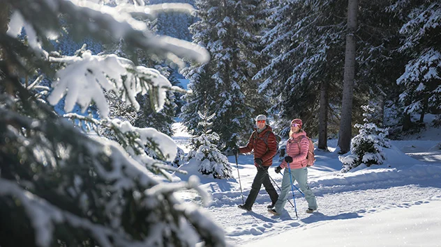Ein Paar wandert durch die verschneite Winterlandschaft. 