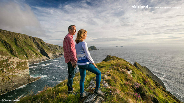 Paar blickt von einem Hügel auf das Meer vor Irland
