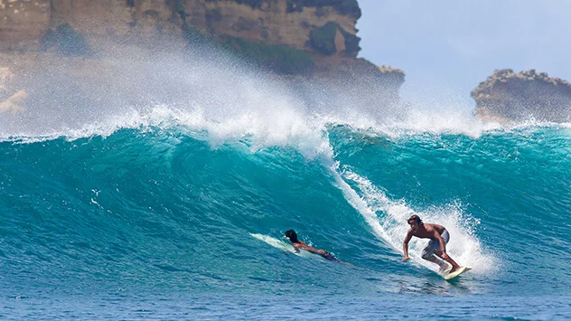 Zwei Surfer reiten auf einer Welle vor Lombok