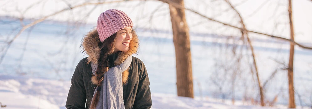 Junge Frau geht in der Sonne im Schnee spazieren