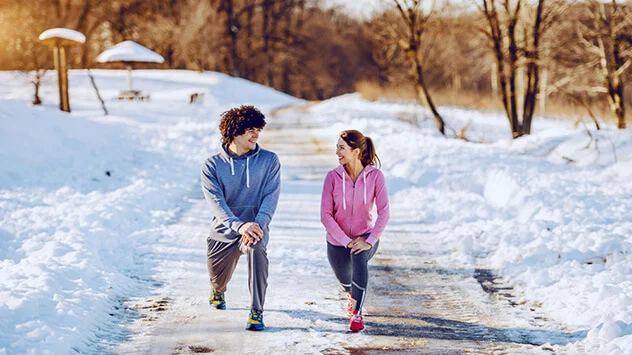 Frau und Mann dehnen sich beim Sport im Winter