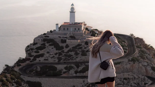 Frau blickt auf den Leuchtturm am Cap de Formentor auf Mallorca.