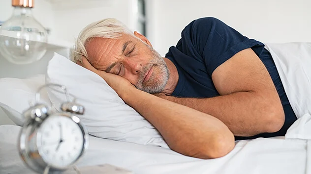 Mann mit Bart schläft auf der Seite in einem Bett