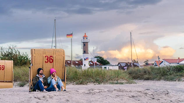 Ein Paar lehnt am Strand auf der Insel Poel an einem Strandkorb