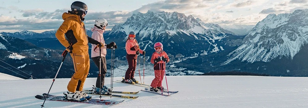 Eine Familie auf Skiern vor einer Bergkulisse. 