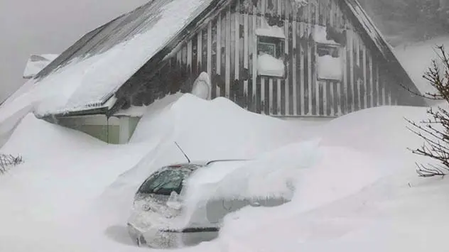 Schneemassen auf Dächern und Autos in den Alpen