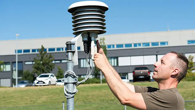 Soldat verbindet Kabel mit Element einer Wetterstation