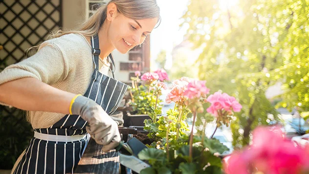 Junge Frau gießt Blumen auf dem Balkon